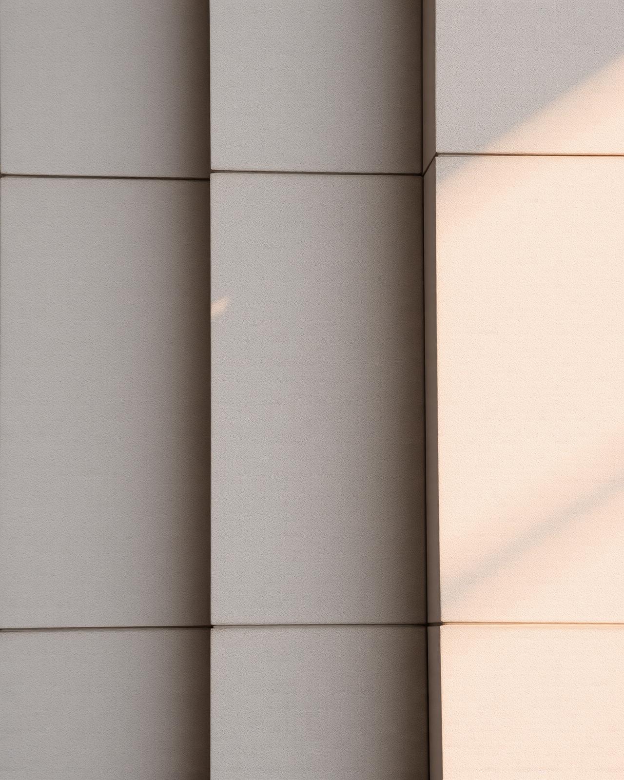 Detail of a layered limestone facade lit by raking sunlight.